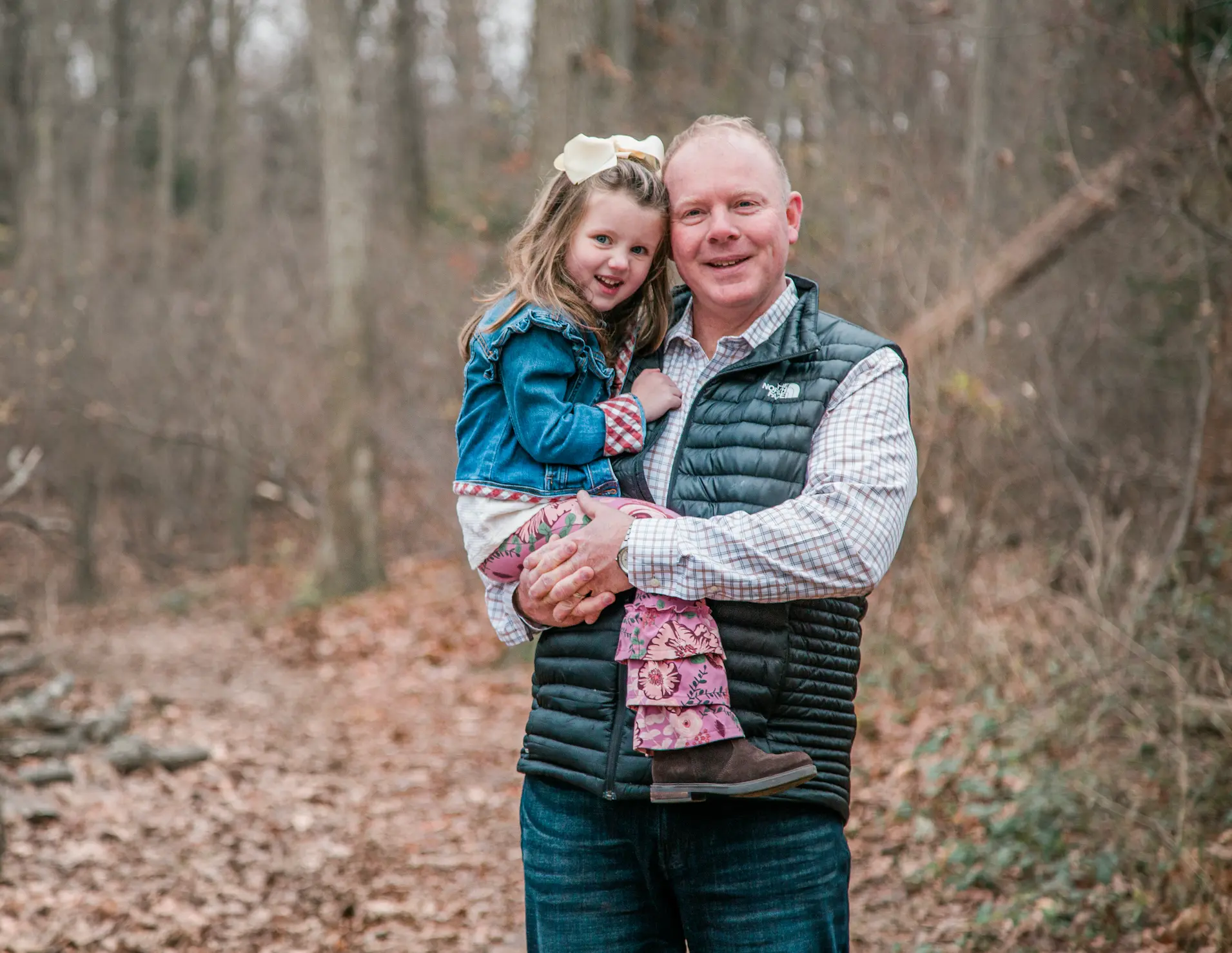 Father holding his young daughter on an autumn woodland trail